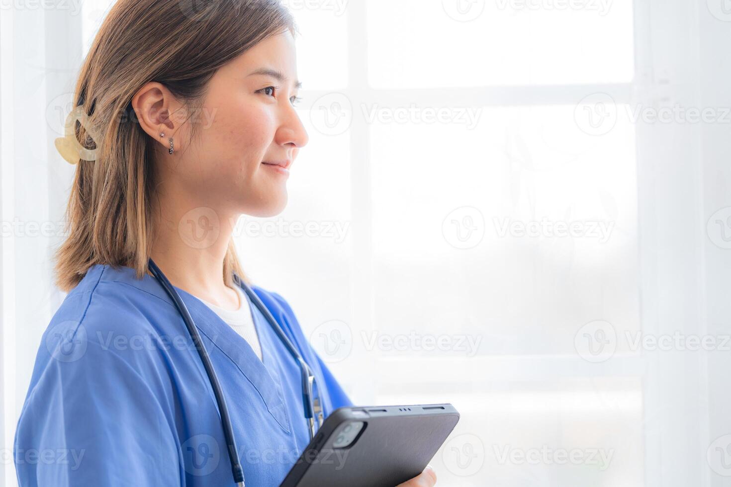 Asian Female medical assistant with smart tablet in white background. Portrait of mature female nurse working in hospital. Woman healthcare worker. Portrait of a good looking young nurse. photo