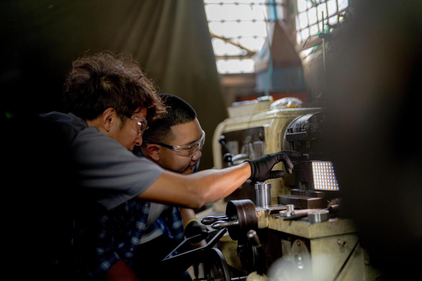 Men are inspecting steel parts for machine installation. team of teacher and student are learning to use heavy machines in steel factory. workers cooperate while doing quality control of manufactured. photo