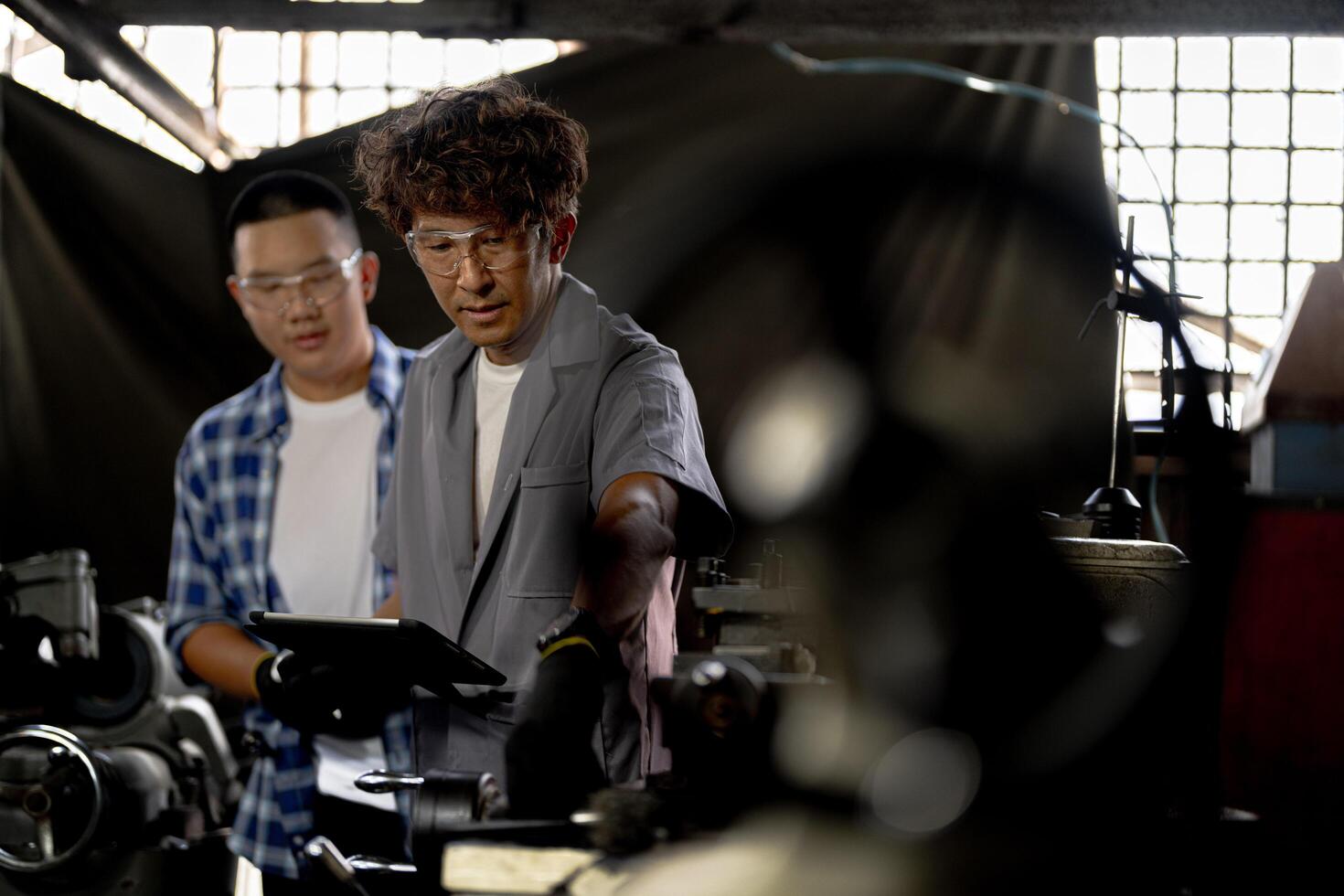 Men are inspecting steel parts for machine installation. team of teacher and student are learning to use heavy machines in steel factory. workers cooperate while doing quality control of manufactured. photo