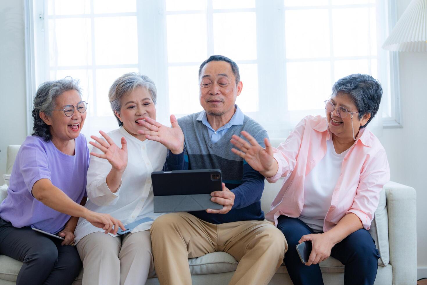 Happiness of the group females and male elderly talking with Call from smart tablet. Senior people are talking and enjoy together at the living room. Joyful retired friends enjoying relaxation. photo