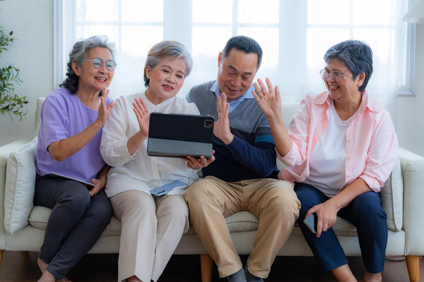 Happiness of the group females and male elderly talking with Call from smart tablet. Senior people are talking and enjoy together at the living room. Joyful retired friends enjoying relaxation. photo