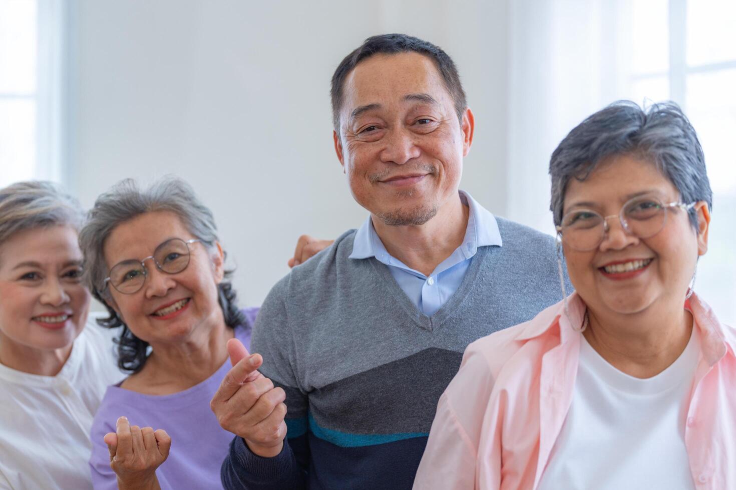 group of asian senior people standing with smart confidence. older people are listening and enjoy meeting focus group at living room. Joyful carefree retired senior friends enjoying relaxation. photo