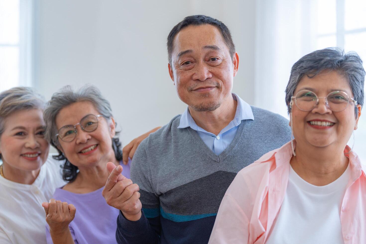 group of asian senior people standing with smart confidence. older people are listening and enjoy meeting focus group at living room. Joyful carefree retired senior friends enjoying relaxation. photo