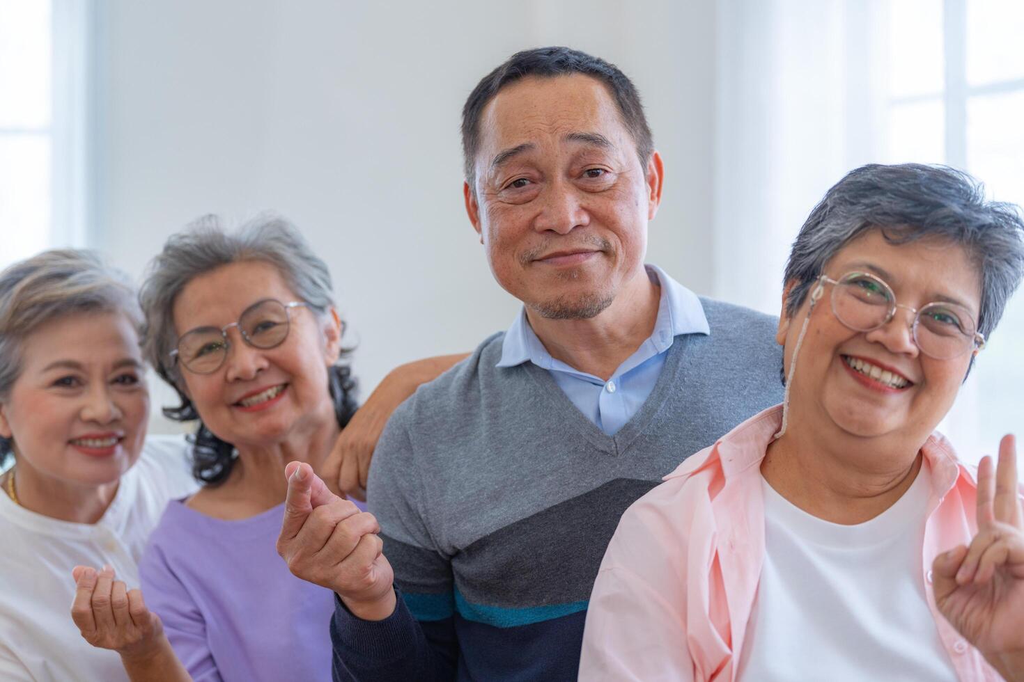 group of asian senior people standing with smart confidence. older people are listening and enjoy meeting focus group at living room. Joyful carefree retired senior friends enjoying relaxation. photo