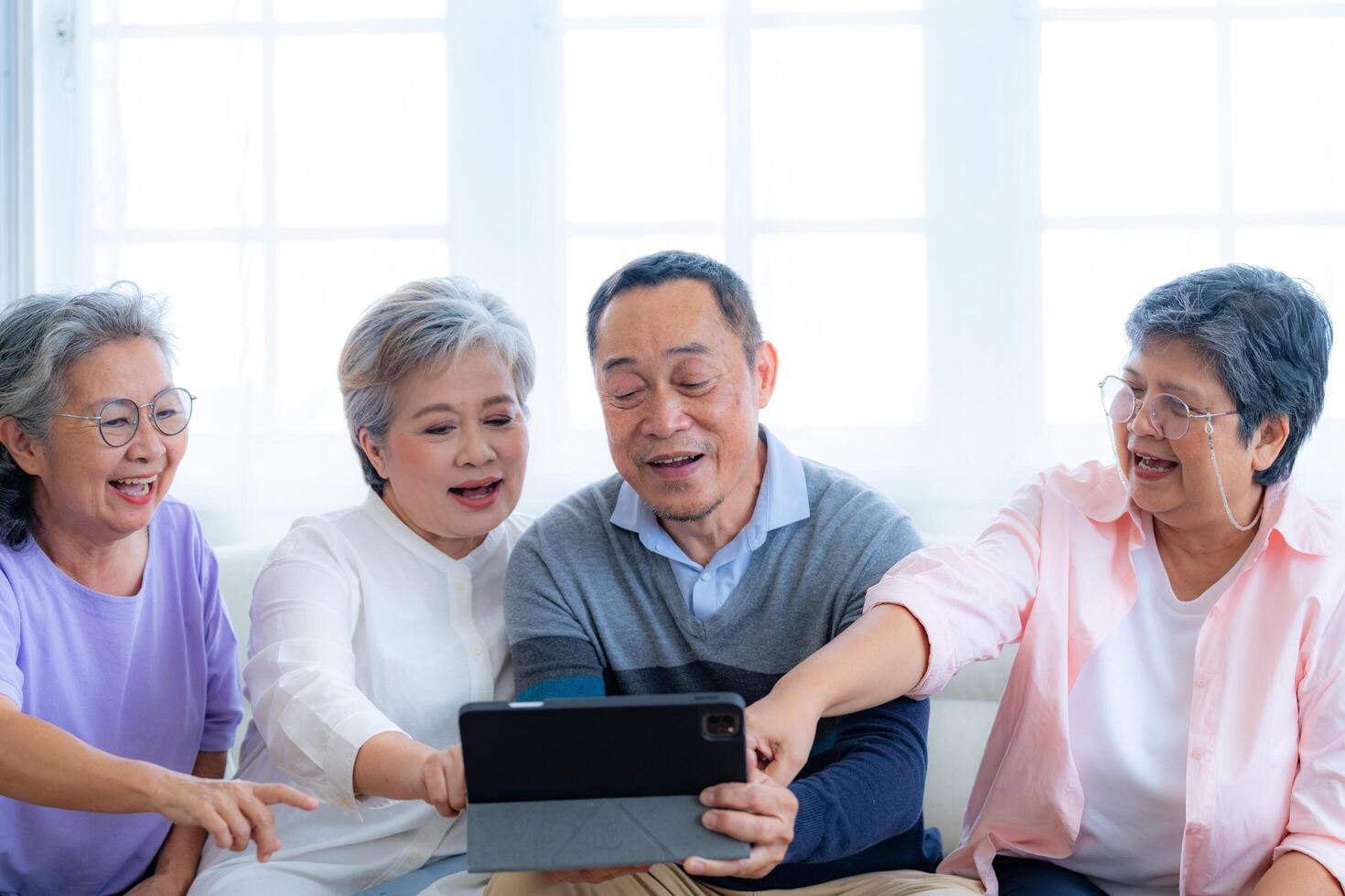 Happiness of the group females and male elderly talking with Call from smart tablet. Senior people are talking and enjoy together at the living room. Joyful retired friends enjoying relaxation. photo