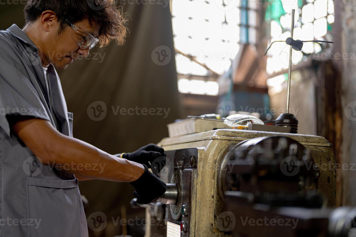 Asian worker in production plant drilling at machine. Professional worker near drilling machine on factory. finishing metal working internal steel surface on lathe grinder machine with flying sparks. photo