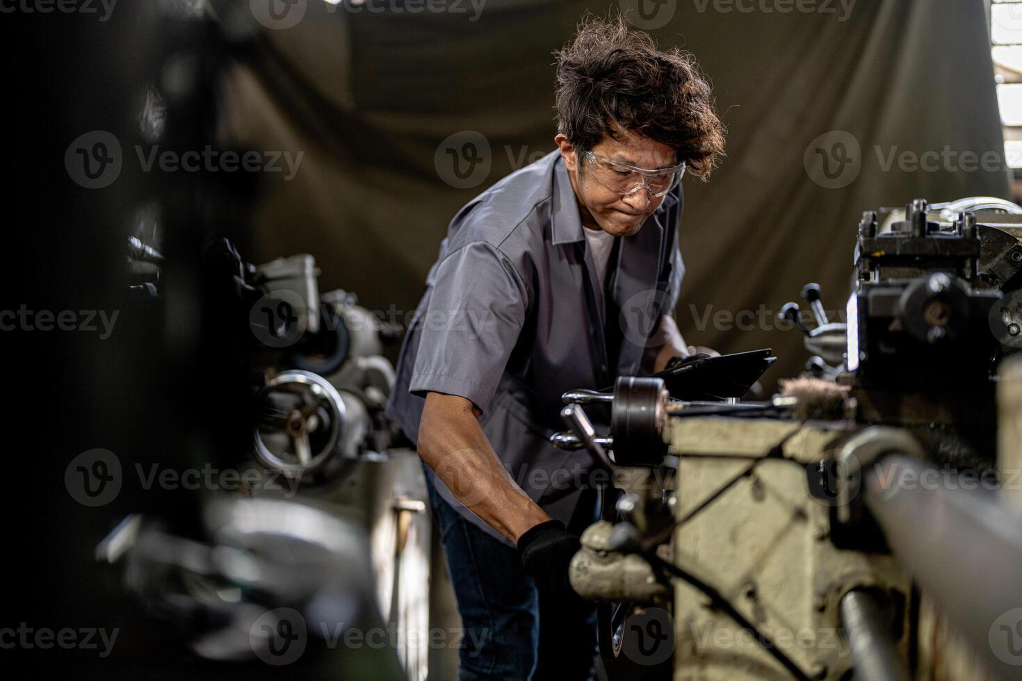 Asian worker in production plant drilling at machine. Professional worker near drilling machine on factory. finishing metal working internal steel surface on lathe grinder machine with flying sparks. photo