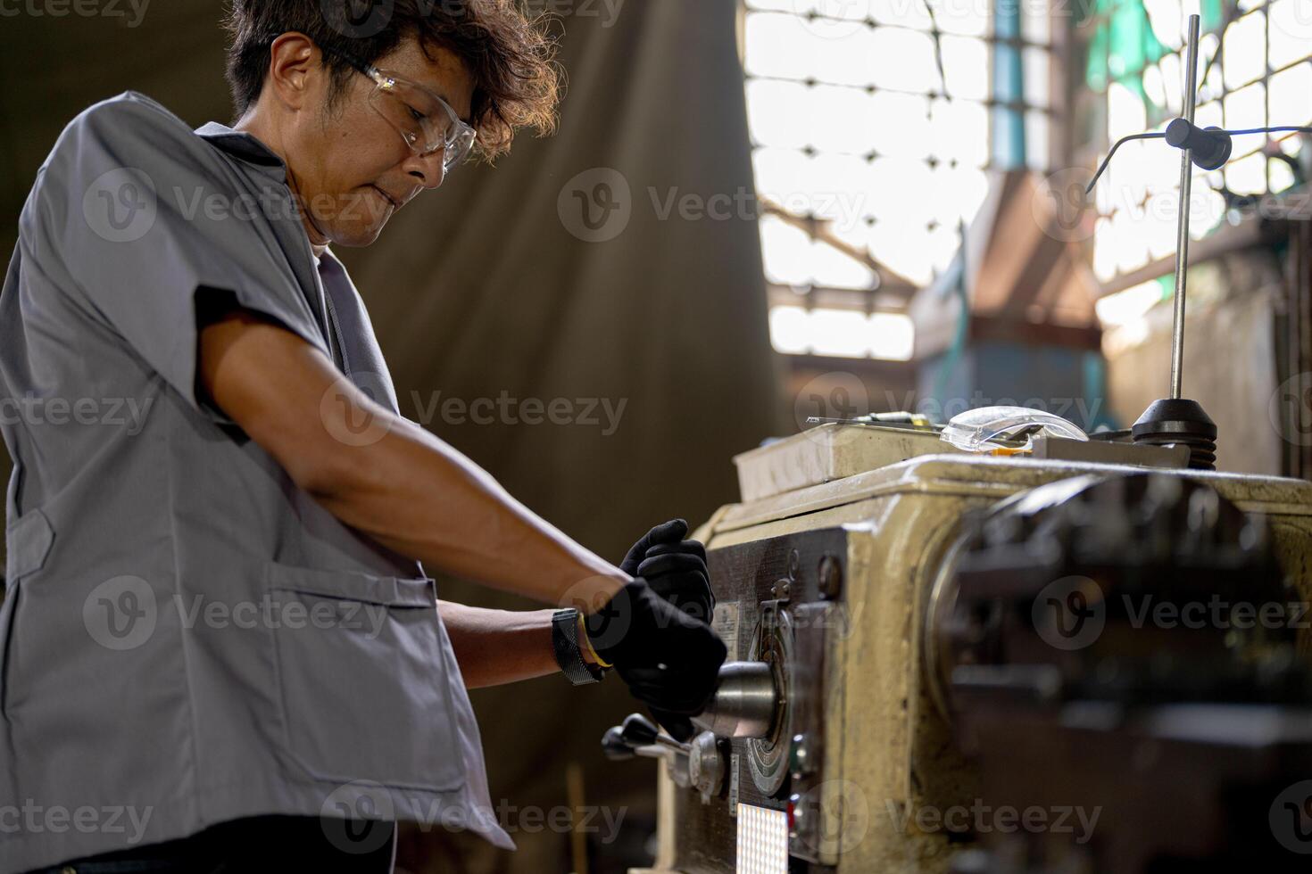 Asian worker in production plant drilling at machine. Professional worker near drilling machine on factory. finishing metal working internal steel surface on lathe grinder machine with flying sparks. photo