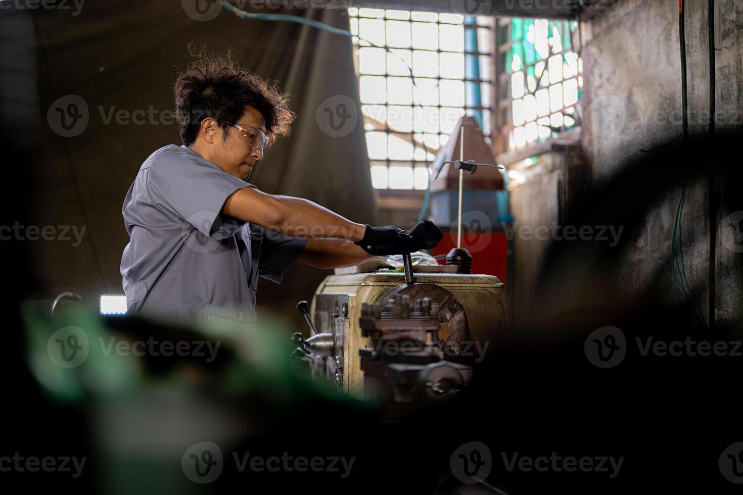 Asian worker in production plant drilling at machine. Professional worker near drilling machine on factory. finishing metal working internal steel surface on lathe grinder machine with flying sparks. photo