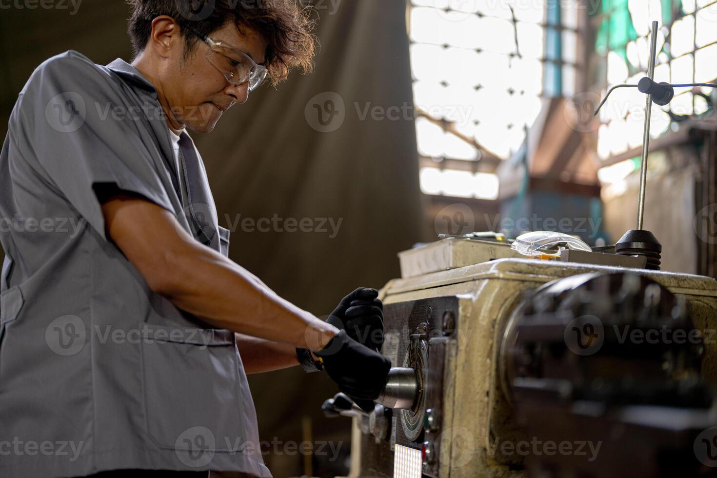Asian worker in production plant drilling at machine. Professional worker near drilling machine on factory. finishing metal working internal steel surface on lathe grinder machine with flying sparks. photo