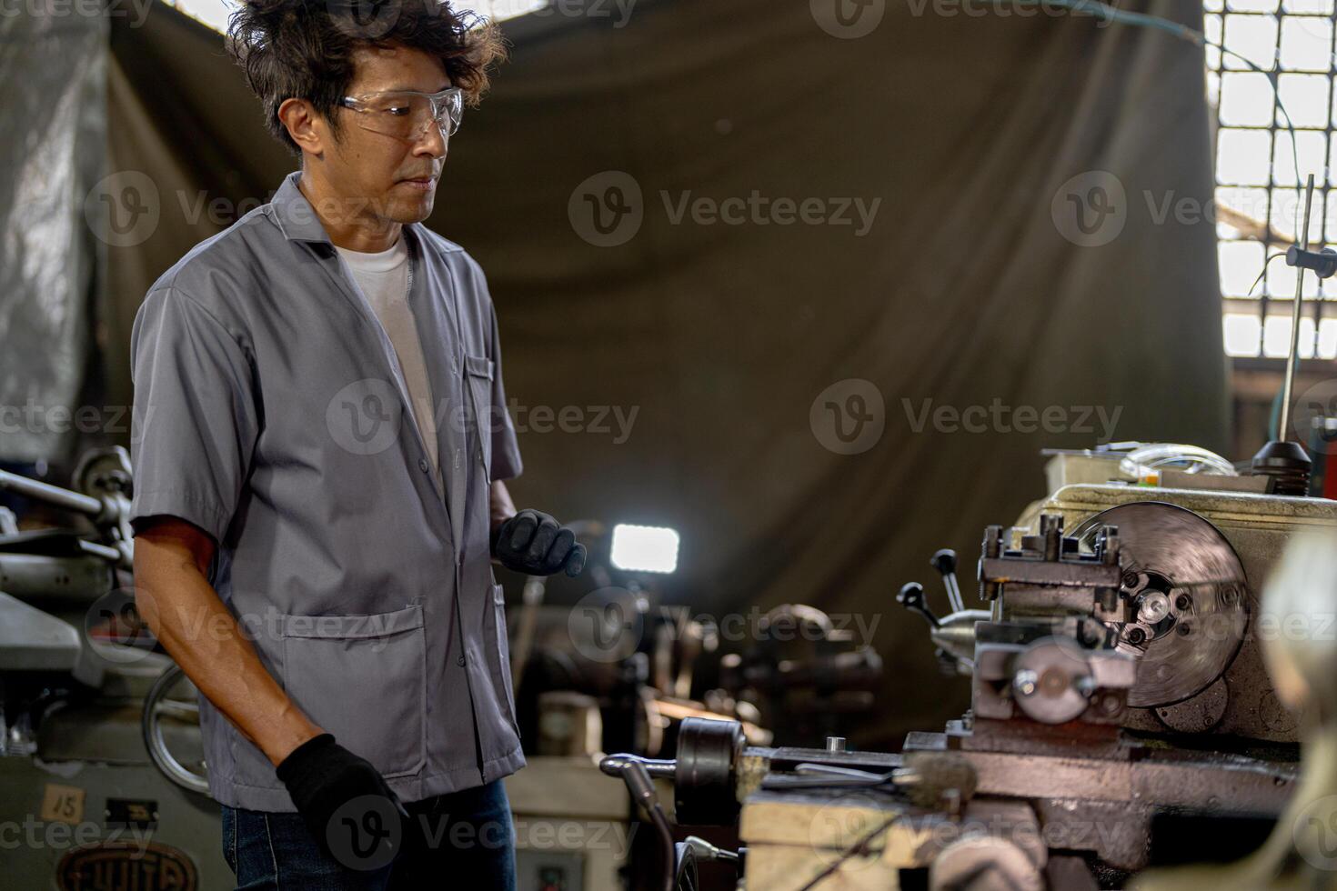 Asian worker in production plant drilling at machine. Professional worker near drilling machine on factory. finishing metal working internal steel surface on lathe grinder machine with flying sparks. photo