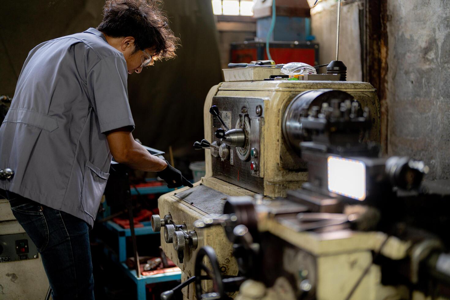 Asian worker in production plant drilling at machine. Professional worker near drilling machine on factory. finishing metal working internal steel surface on lathe grinder machine with flying sparks. photo