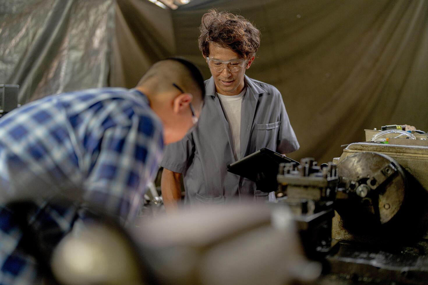 Men are inspecting steel parts for machine installation. team of teacher and student are learning to use heavy machines in steel factory. workers cooperate while doing quality control of manufactured. photo