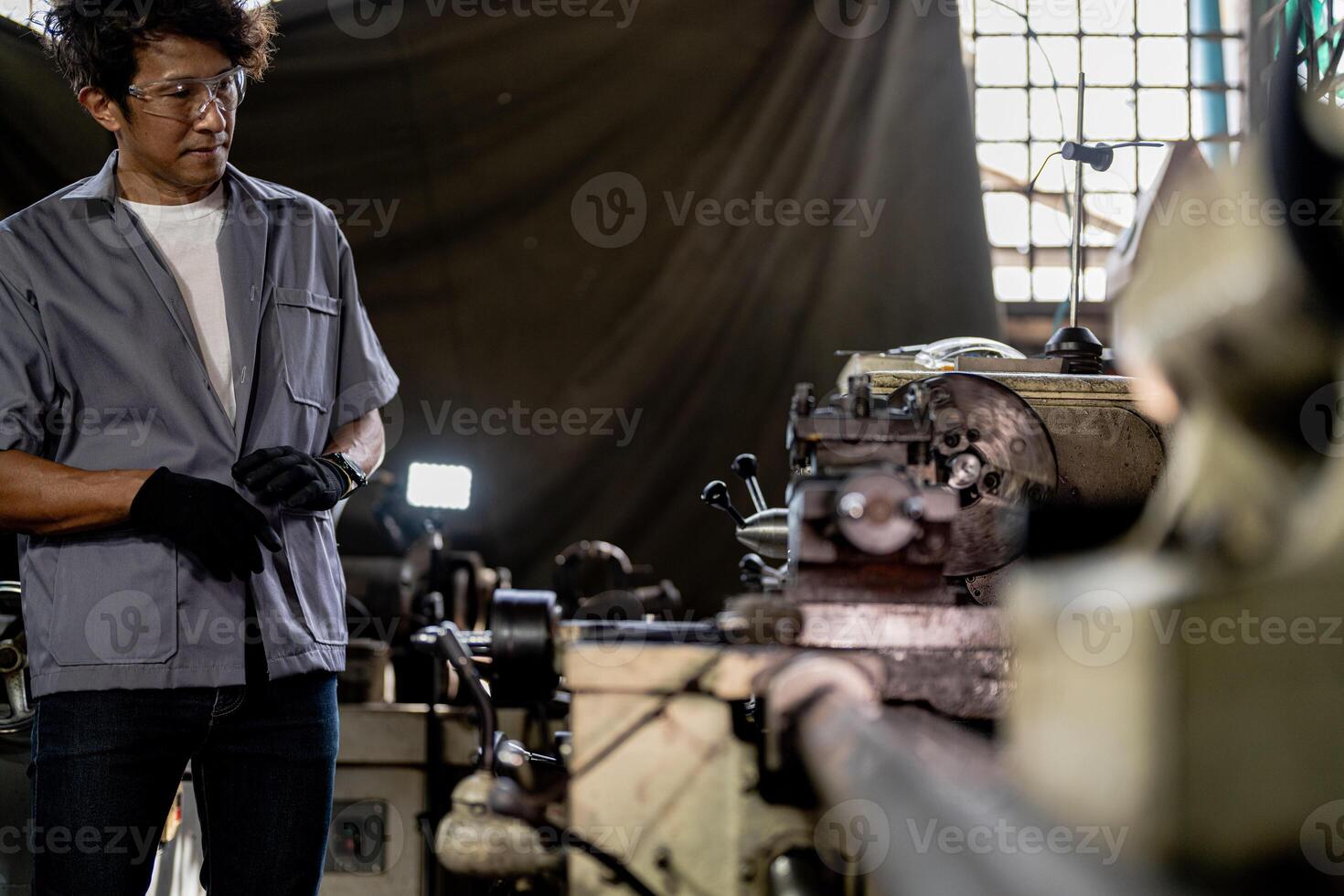 Asian worker in production plant drilling at machine. Professional worker near drilling machine on factory. finishing metal working internal steel surface on lathe grinder machine with flying sparks. photo