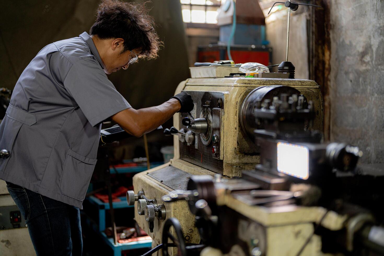 Asian worker in production plant drilling at machine. Professional worker near drilling machine on factory. finishing metal working internal steel surface on lathe grinder machine with flying sparks. photo