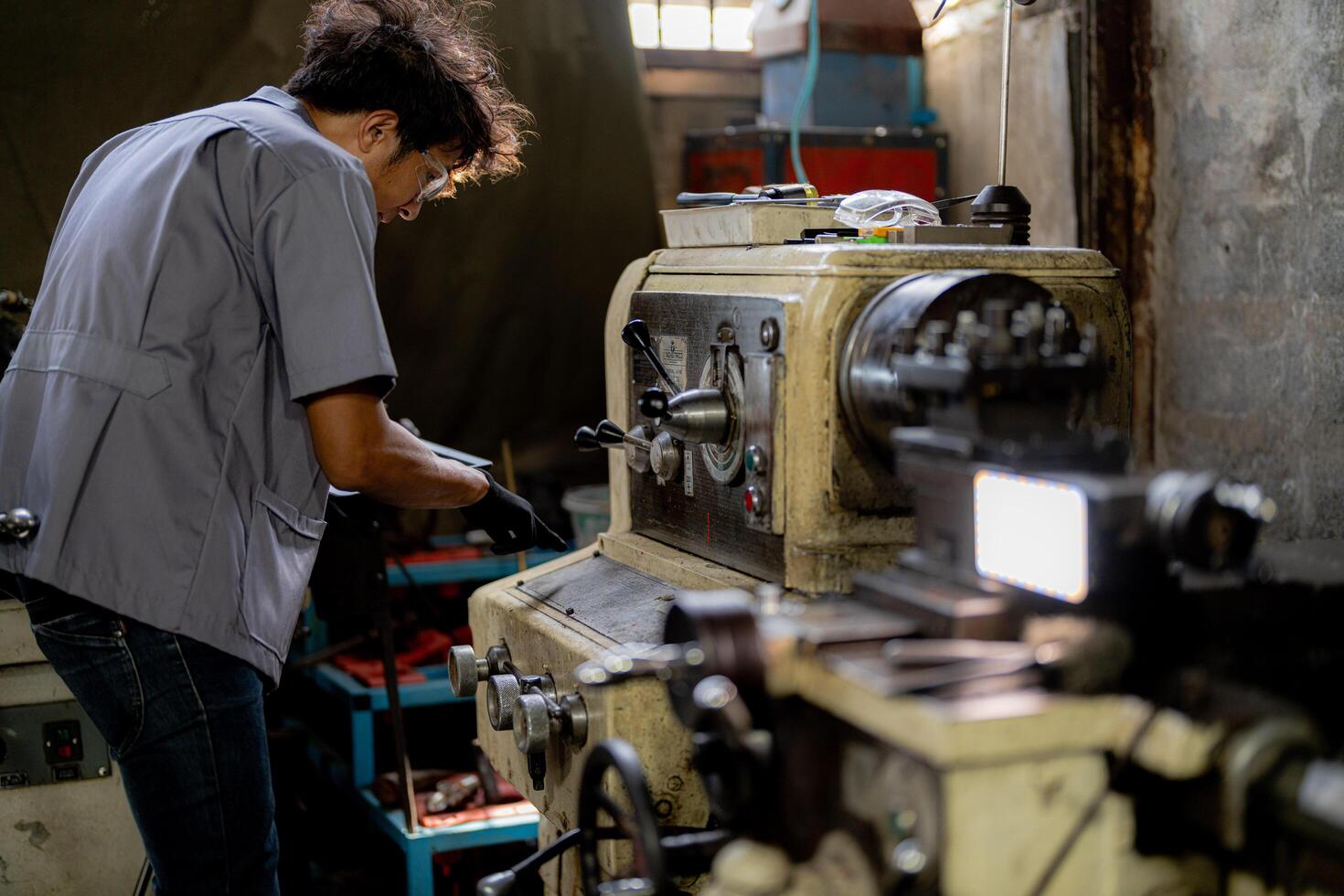 Asian worker in production plant drilling at machine. Professional worker near drilling machine on factory. finishing metal working internal steel surface on lathe grinder machine with flying sparks. photo