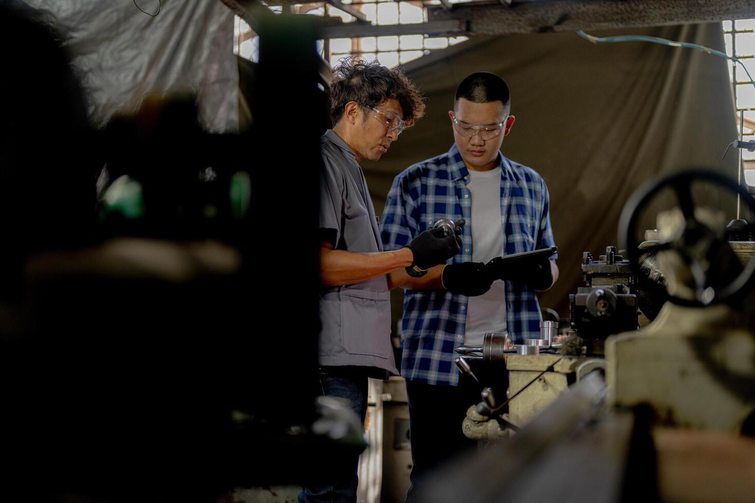 Men are inspecting steel parts for machine installation. team of teacher and student are learning to use heavy machines in steel factory. workers cooperate while doing quality control of manufactured. photo