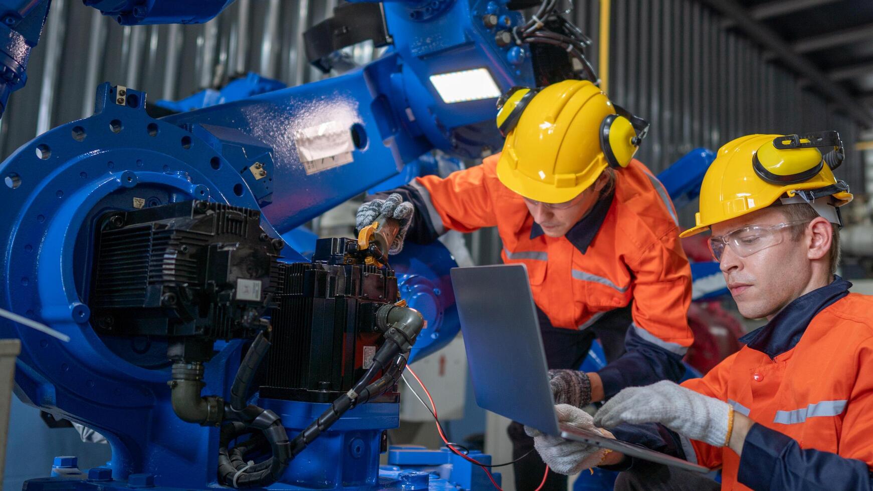 group of male engineer workers maintenance automatic robotic arm machine in a dark room factory. worker checking and repairing automatic robot hand machine. Worker wearing safety glasses and helmet. photo