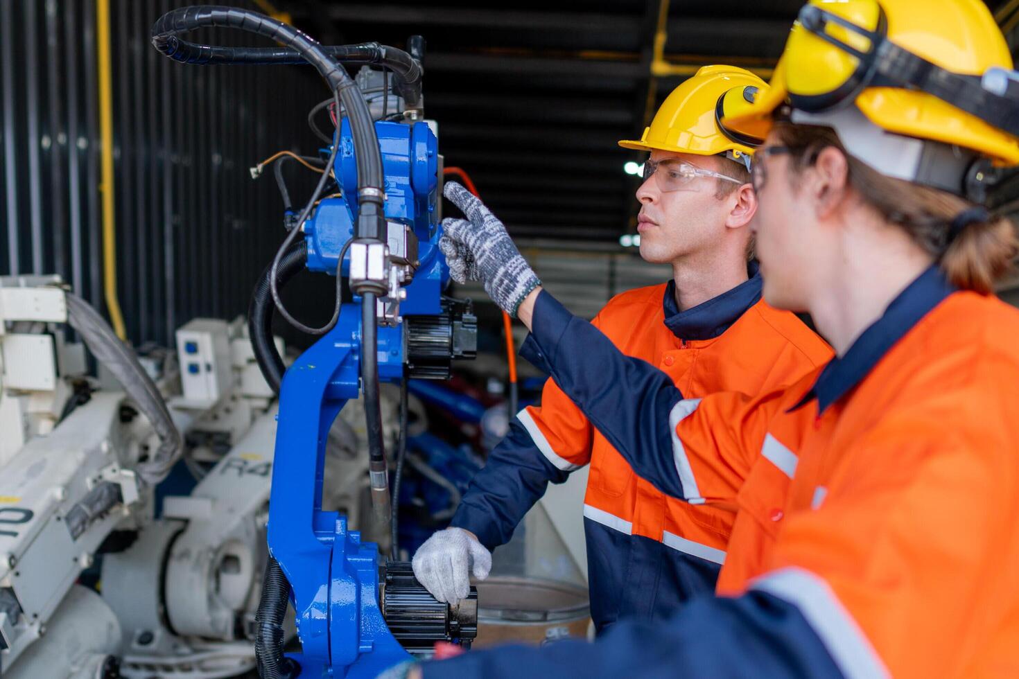 group of male engineer workers maintenance automatic robotic arm machine in a dark room factory. worker checking and repairing automatic robot hand machine. Worker wearing safety glasses and helmet. photo