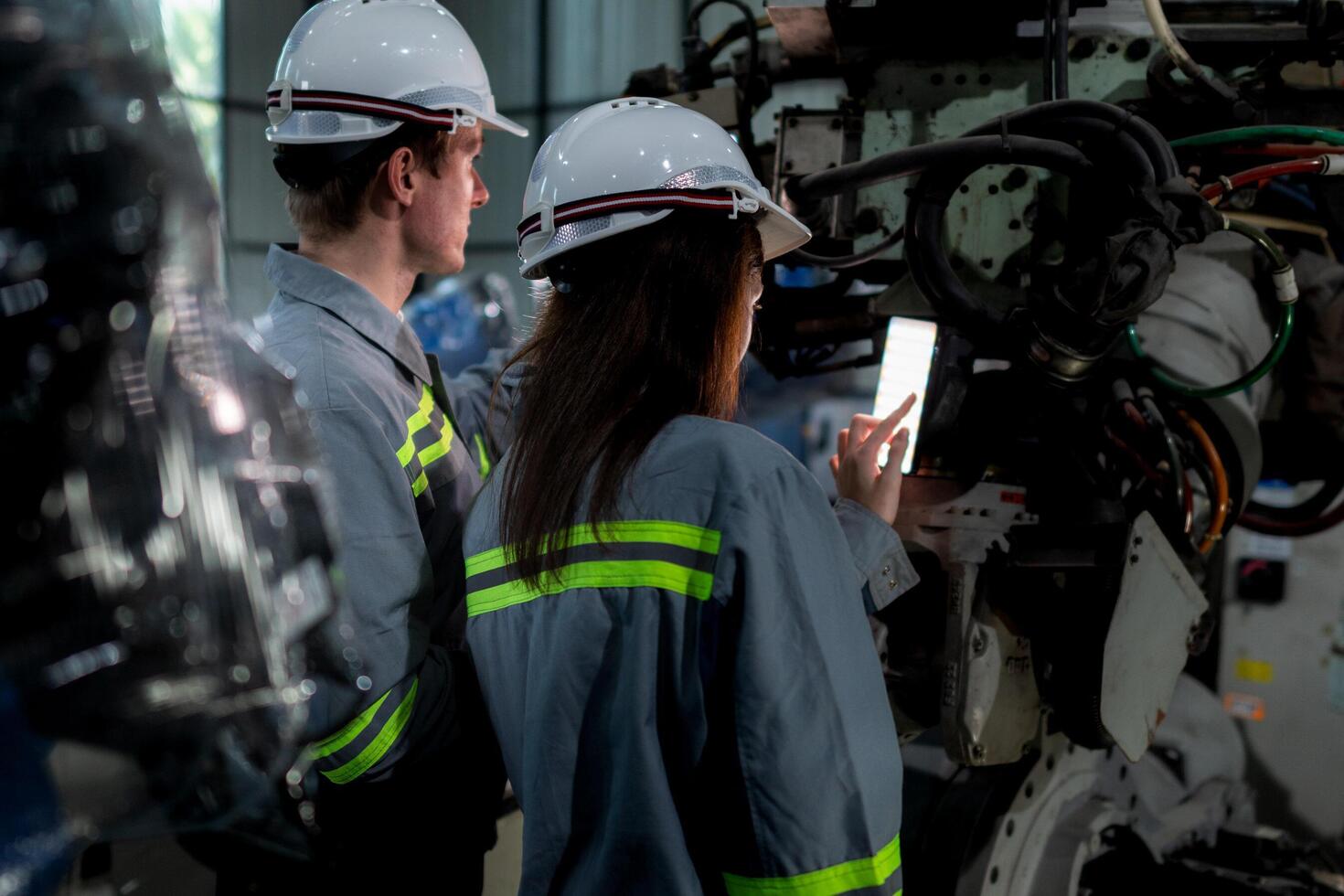 team engineers inspecting on machine with smart tablet. Worker works at heavy machine robot arm. The welding machine with a remote system in an industrial factory. Artificial intelligence concept. photo