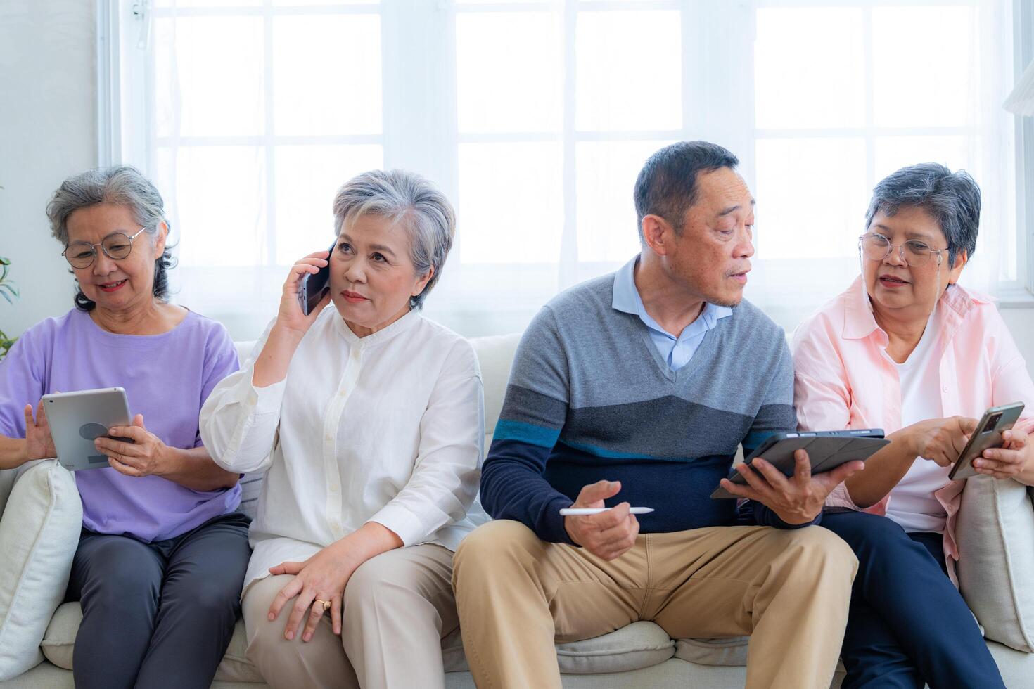 Happiness of the group females and male elderly talking with Call from smart tablet. Senior people are talking and enjoy together at the living room. Joyful retired friends enjoying relaxation. photo