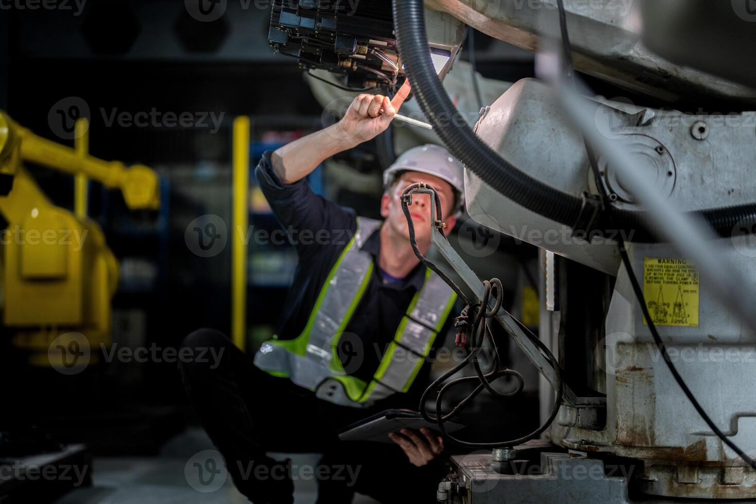 male engineer workers maintenance automatic robotic arm machine in a factory. worker checking and repairing automatic robot hand machine. technician worker check for repair factory machine. photo