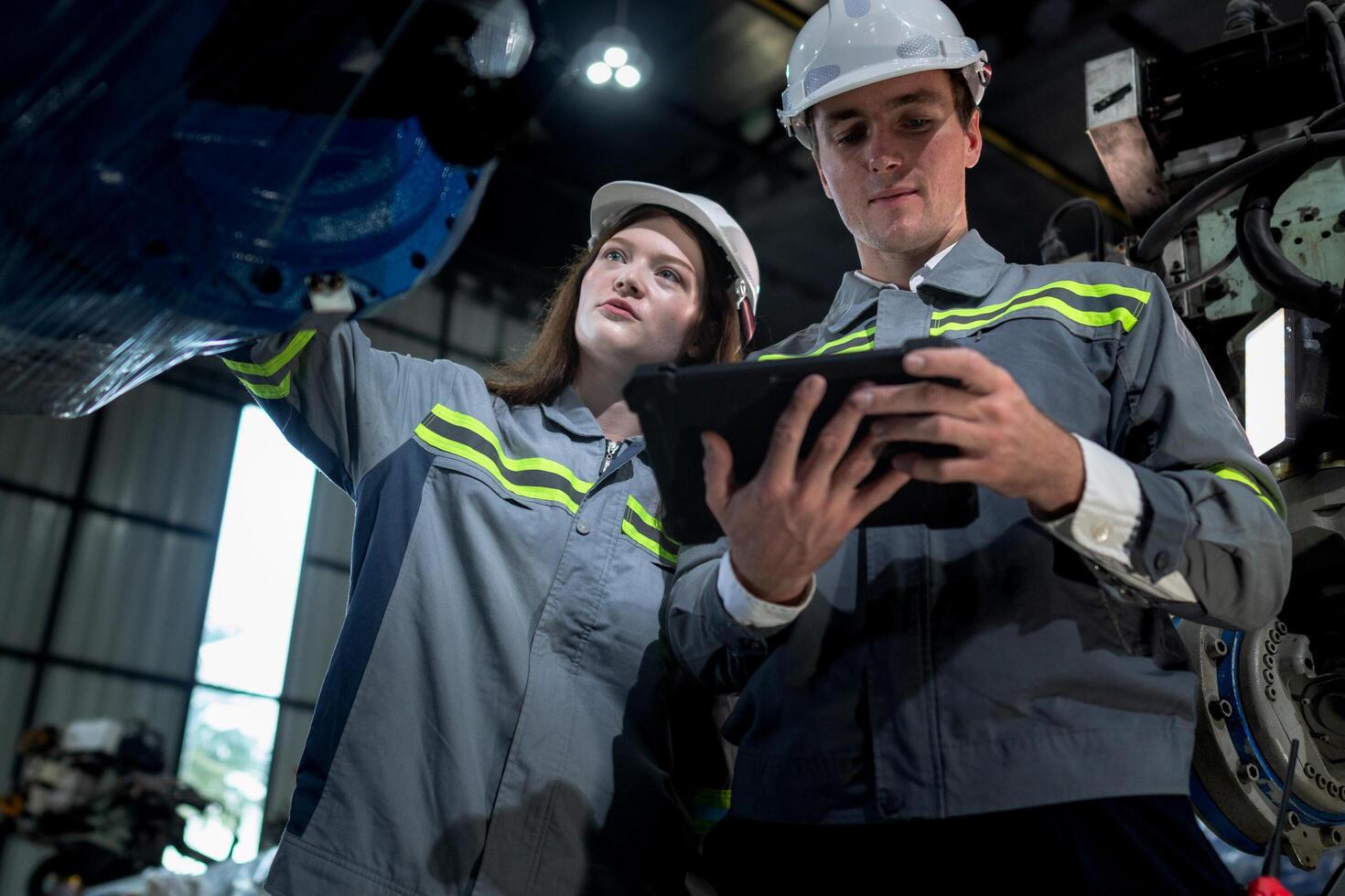 team engineers inspecting on machine with smart tablet. Worker works at heavy machine robot arm. The welding machine with a remote system in an industrial factory. Artificial intelligence concept. photo