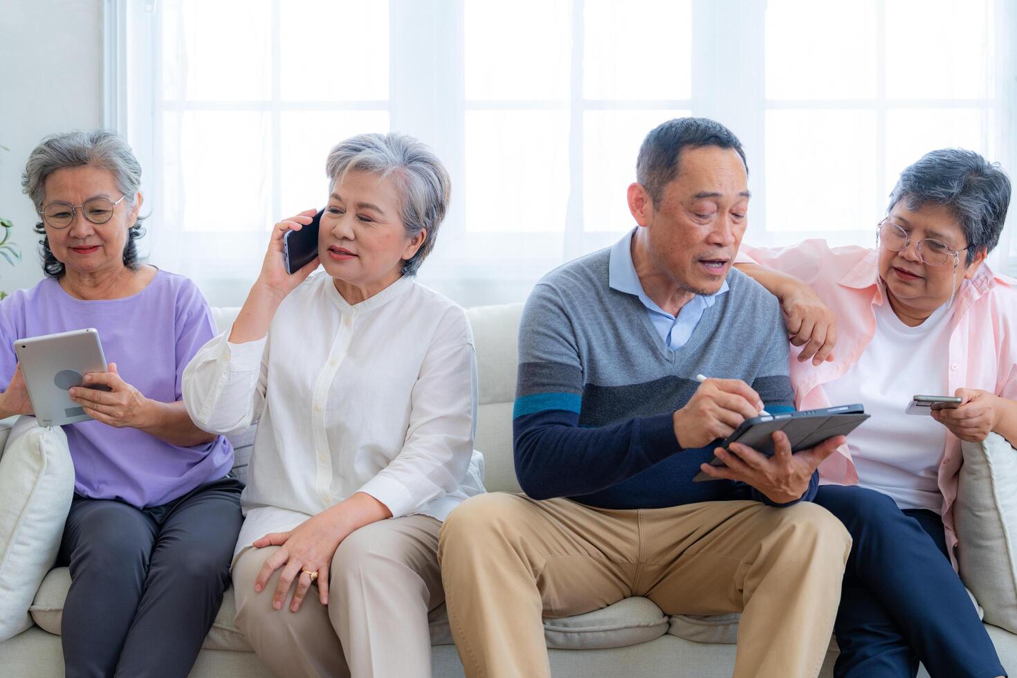 Happiness of the group females and male elderly talking with Call from smart tablet. Senior people are talking and enjoy together at the living room. Joyful retired friends enjoying relaxation. photo