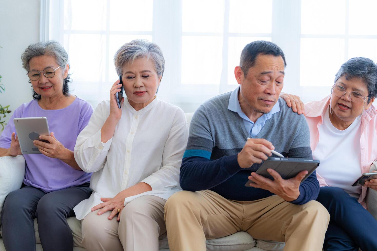 Happiness of the group females and male elderly talking with Call from smart tablet. Senior people are talking and enjoy together at the living room. Joyful retired friends enjoying relaxation. photo