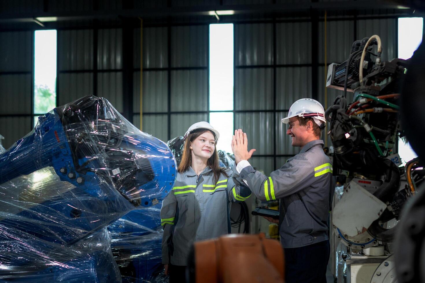 team engineers inspecting on machine with smart tablet. Worker works at heavy machine robot arm. The welding machine with a remote system in an industrial factory. Artificial intelligence concept. photo