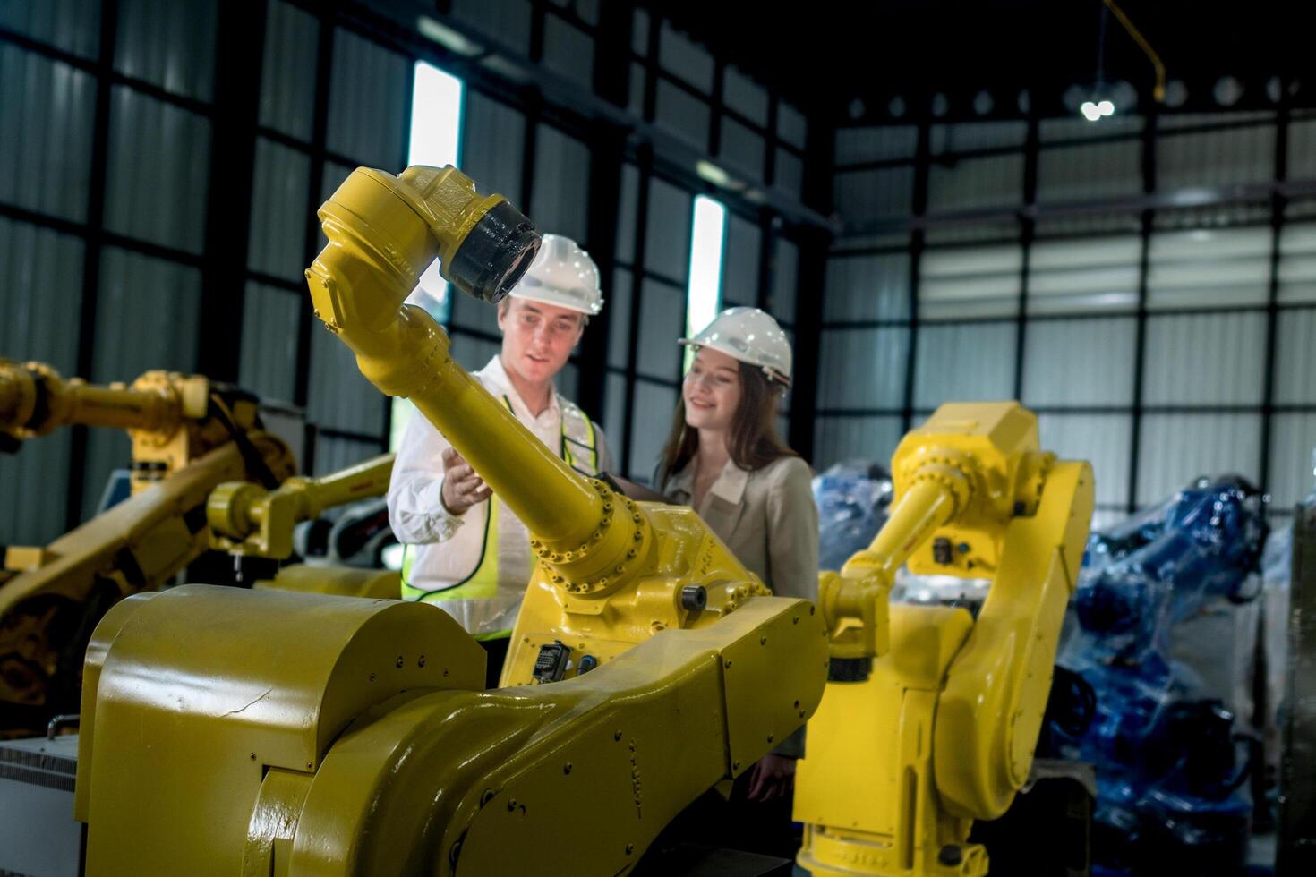 team engineers inspecting on machine with smart tablet. Worker works at heavy machine robot arm. The welding machine with a remote system in an industrial factory. Artificial intelligence concept. photo