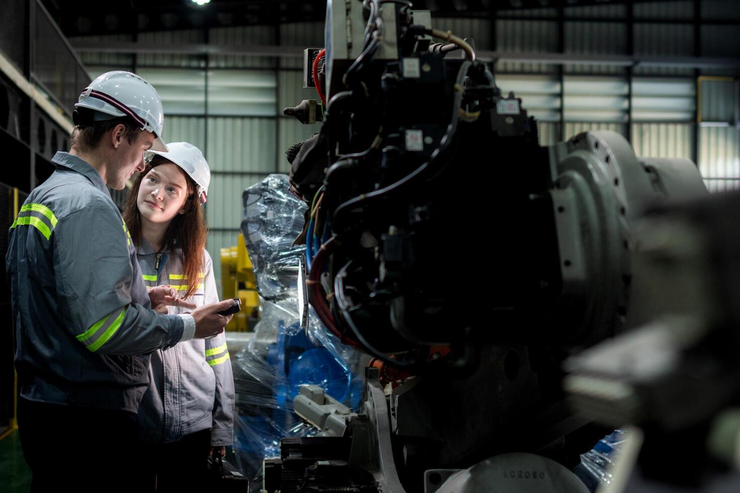 team engineers inspecting on machine with smart tablet. Worker works at heavy machine robot arm. The welding machine with a remote system in an industrial factory. Artificial intelligence concept. photo