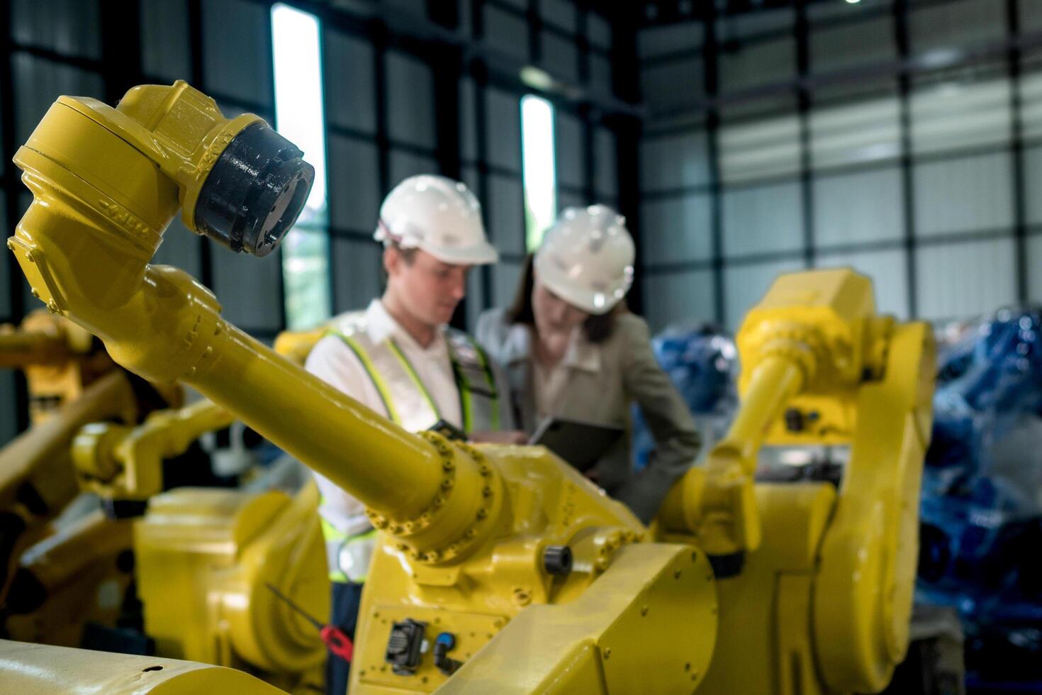 team engineers inspecting on machine with smart tablet. Worker works at heavy machine robot arm. The welding machine with a remote system in an industrial factory. Artificial intelligence concept. photo