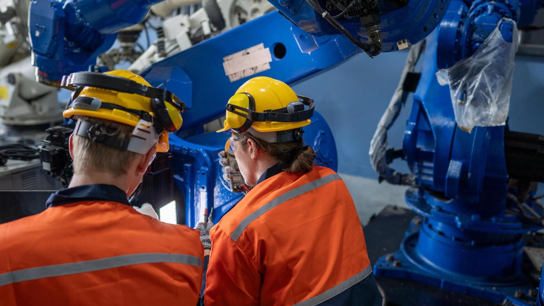 group of male engineer workers maintenance automatic robotic arm machine in a dark room factory. worker checking and repairing automatic robot hand machine. Worker wearing safety glasses and helmet. photo