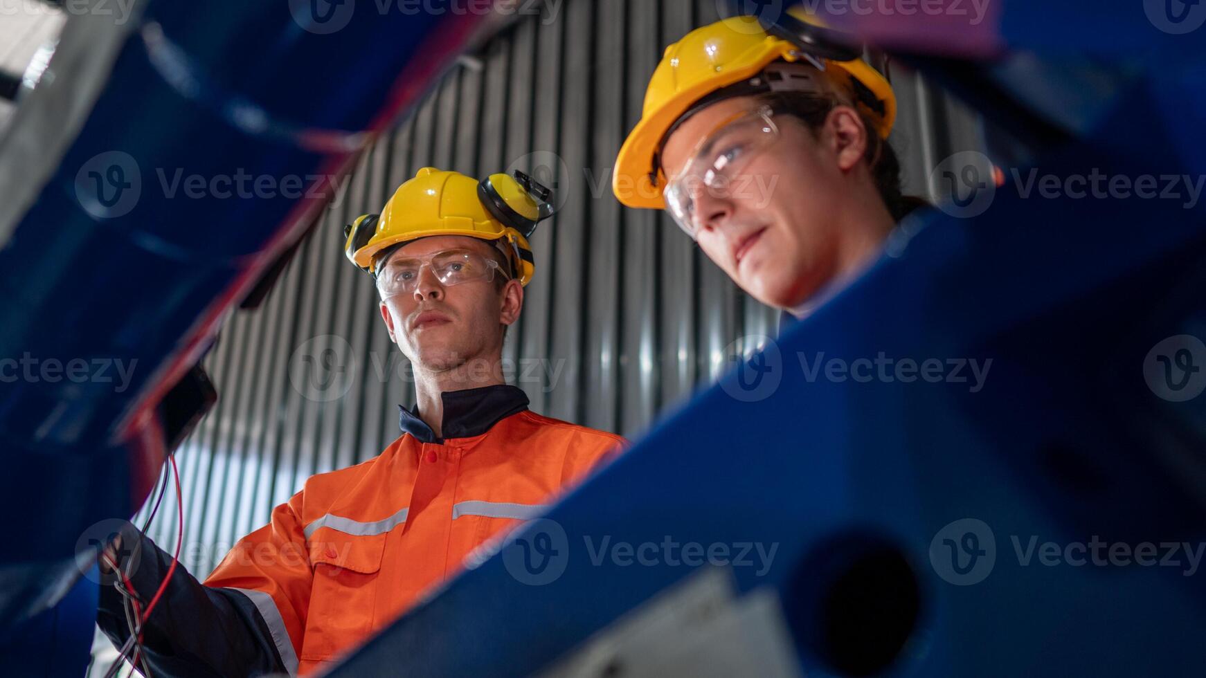 group of male engineer workers maintenance automatic robotic arm machine in a dark room factory. worker checking and repairing automatic robot hand machine. Worker wearing safety glasses and helmet. photo