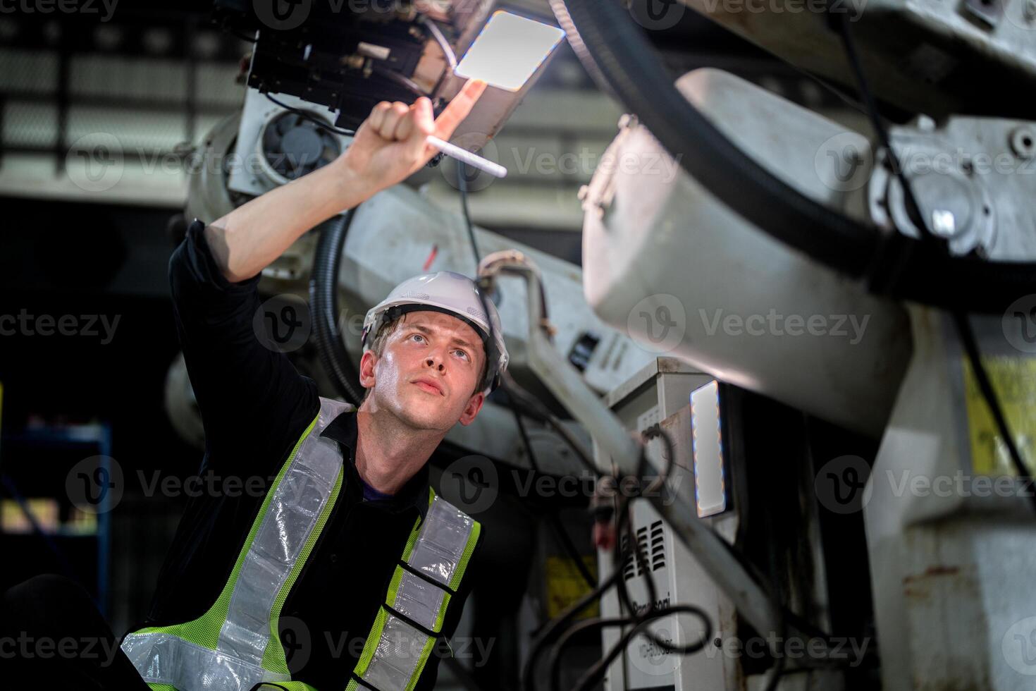male engineer workers maintenance automatic robotic arm machine in a factory. worker checking and repairing automatic robot hand machine. technician worker check for repair factory machine. photo