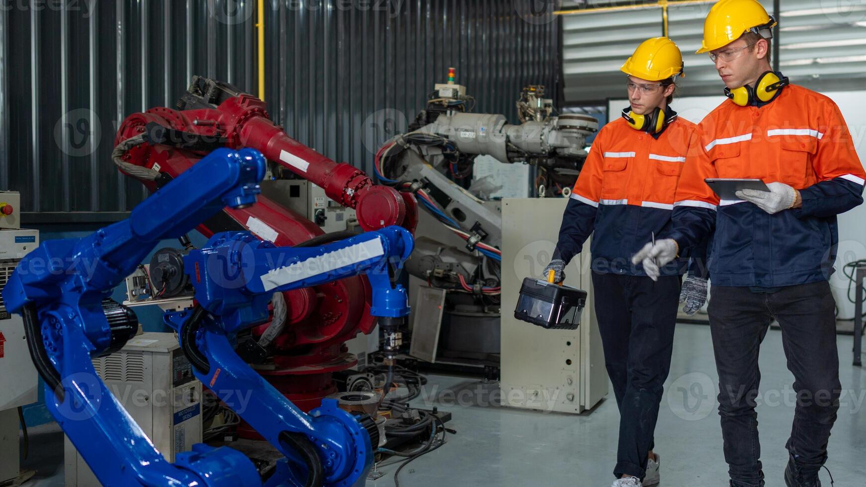 group of male engineer workers maintenance automatic robotic arm machine in a dark room factory. worker checking and repairing automatic robot hand machine. Worker wearing safety glasses and helmet. photo