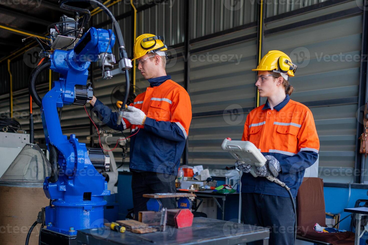 group of male engineer workers maintenance automatic robotic arm machine in a dark room factory. worker checking and repairing automatic robot hand machine. Worker wearing safety glasses and helmet. photo