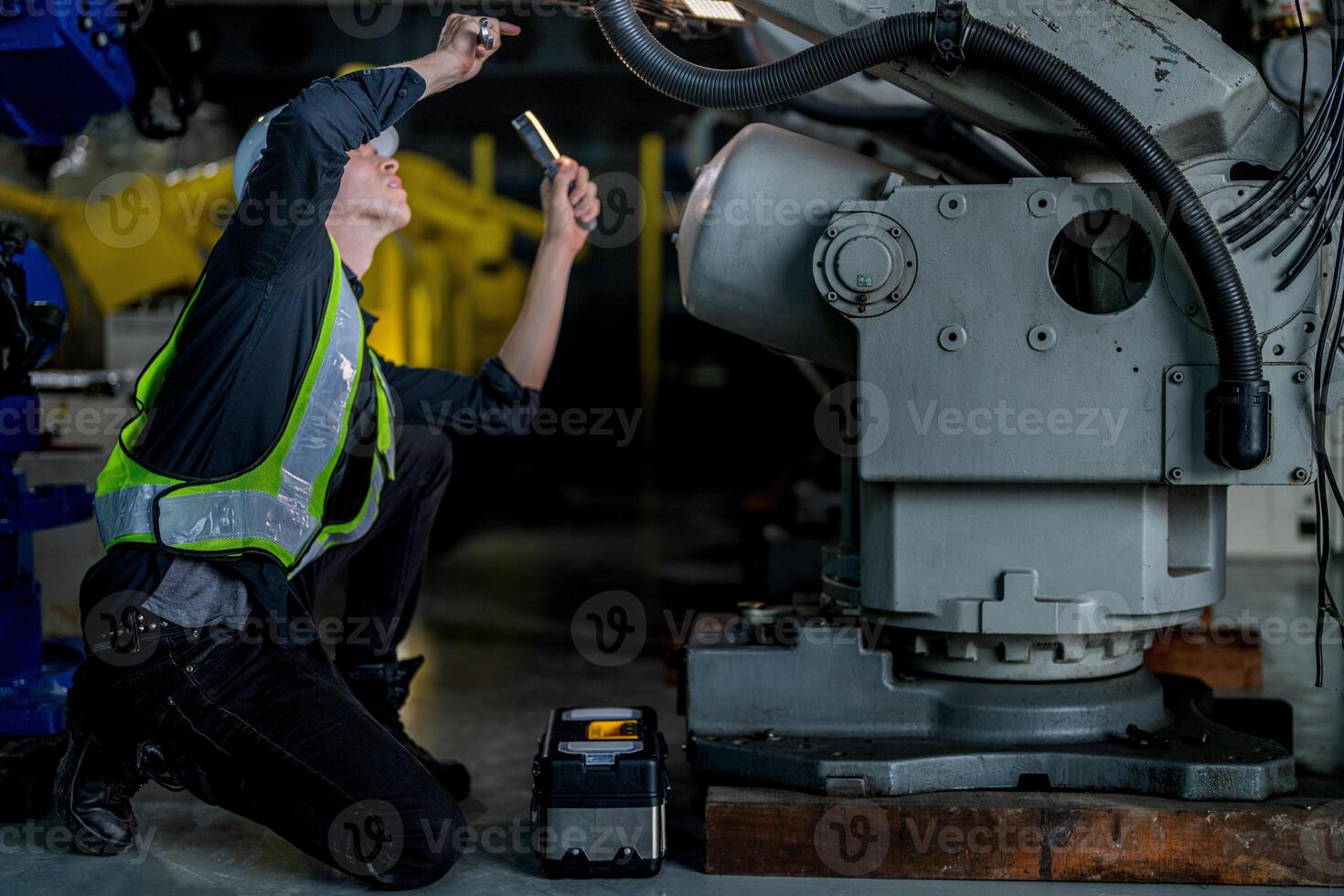 male engineer workers maintenance automatic robotic arm machine in a factory. worker checking and repairing automatic robot hand machine. technician worker check for repair factory machine. photo