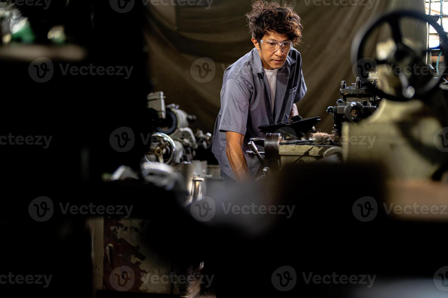 Asian worker in production plant drilling at machine. Professional worker near drilling machine on factory. finishing metal working internal steel surface on lathe grinder machine with flying sparks. photo