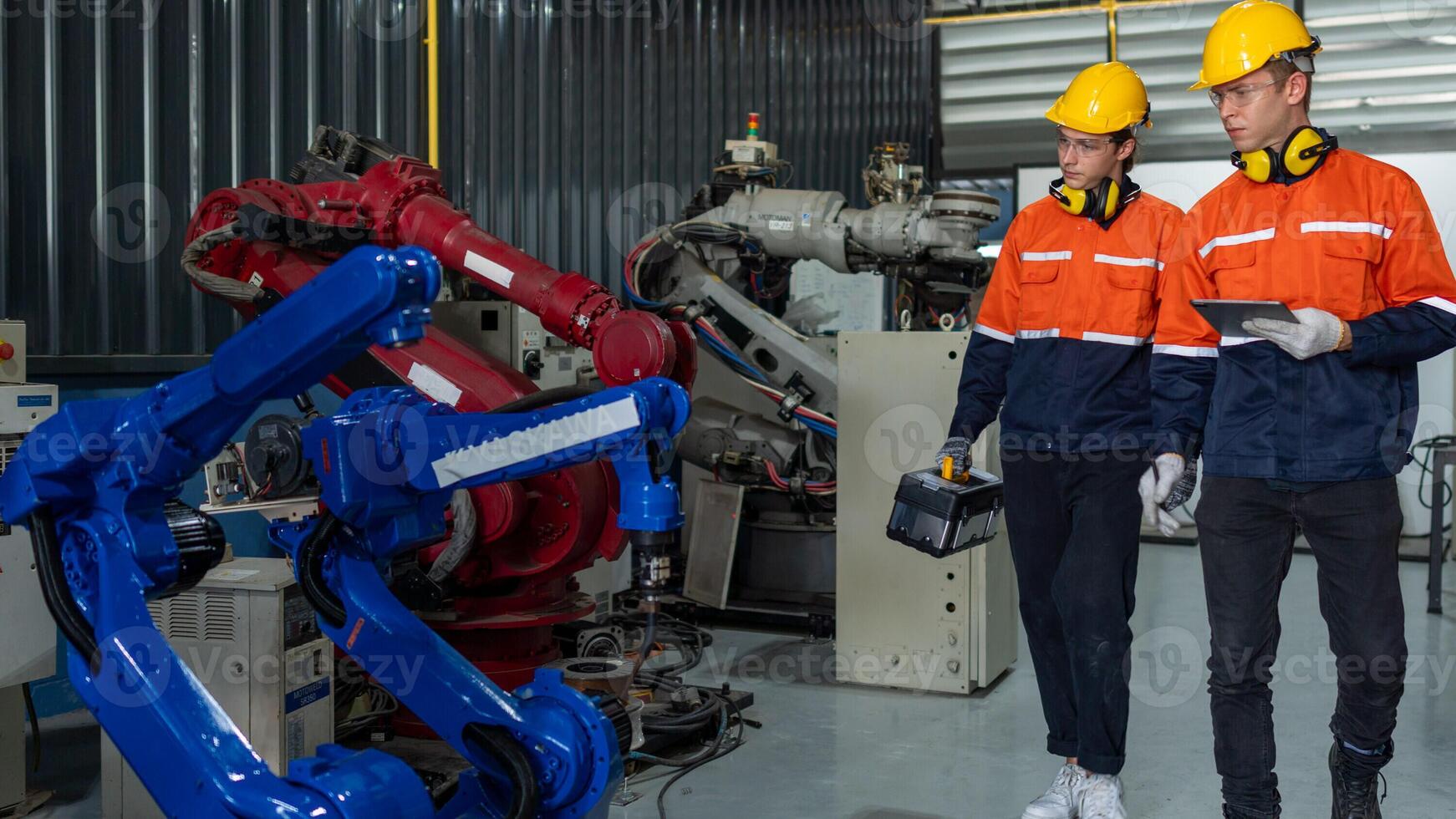 group of male engineer workers maintenance automatic robotic arm machine in a dark room factory. worker checking and repairing automatic robot hand machine. Worker wearing safety glasses and helmet. photo