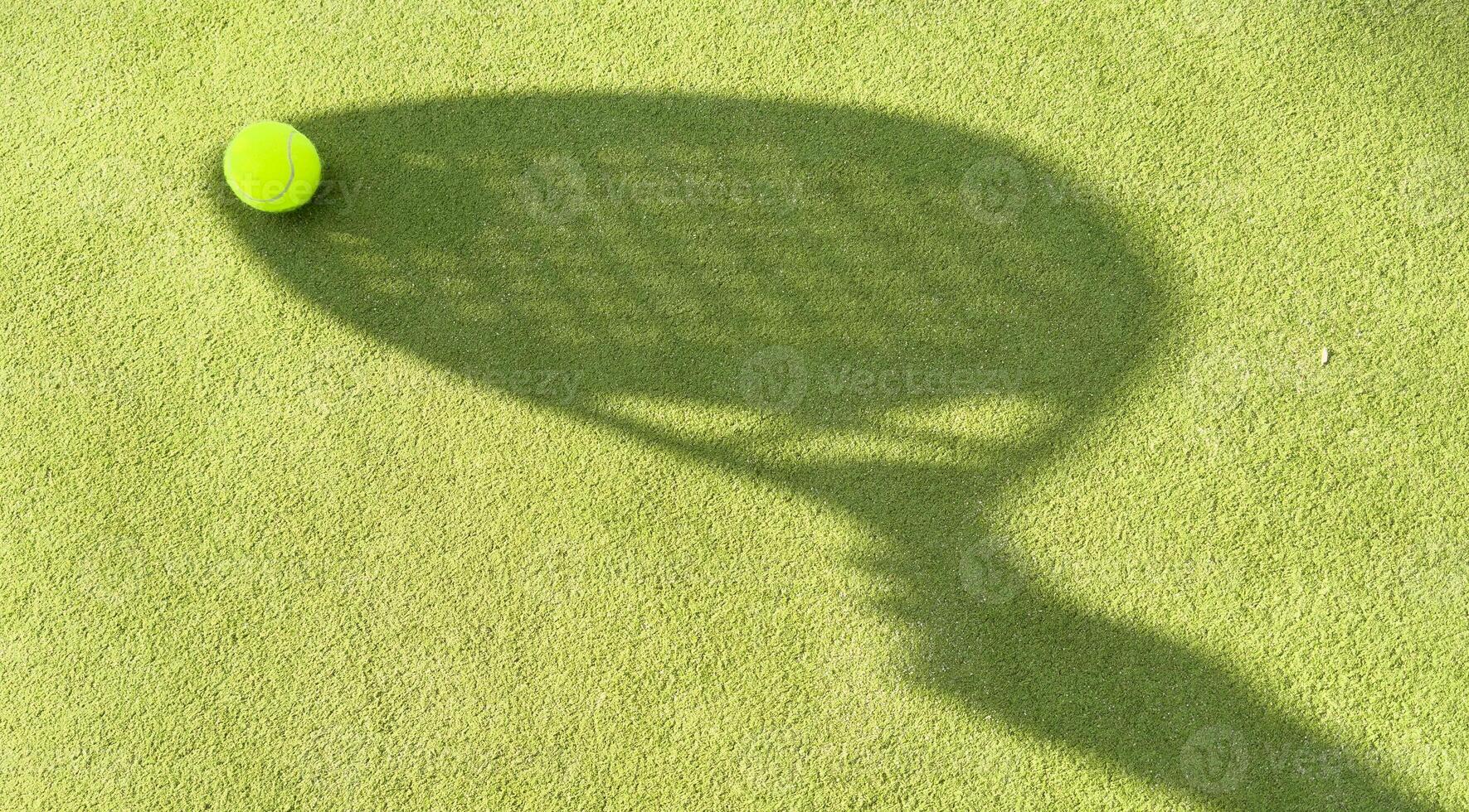 Shadow of a padel racket with a yellow ball on the green grass. photo