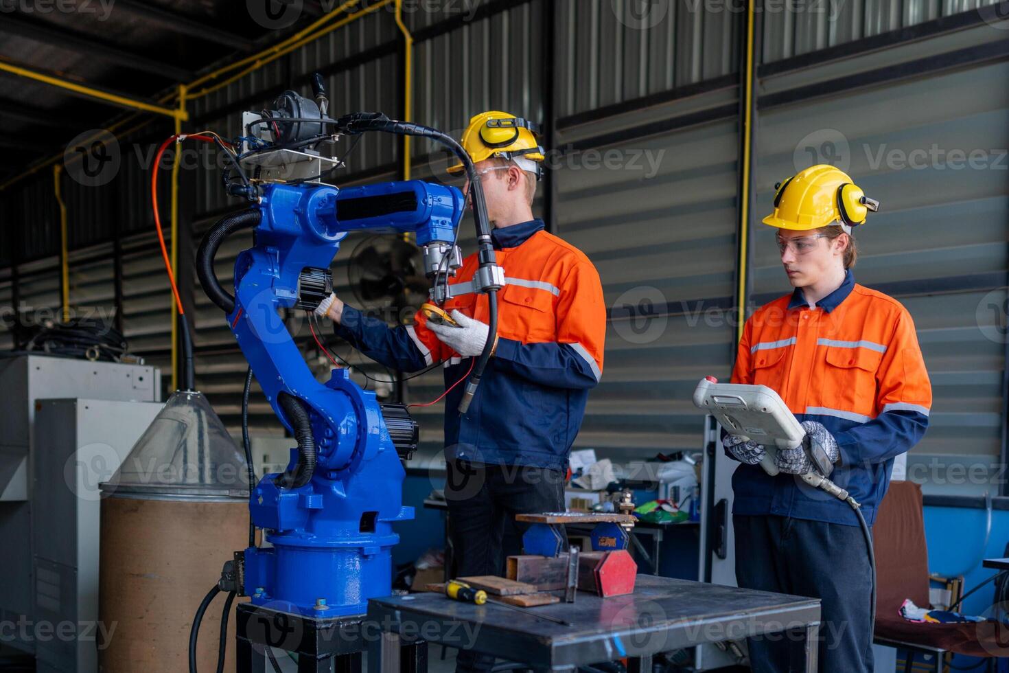 group of male engineer workers maintenance automatic robotic arm machine in a dark room factory. worker checking and repairing automatic robot hand machine. Worker wearing safety glasses and helmet. photo