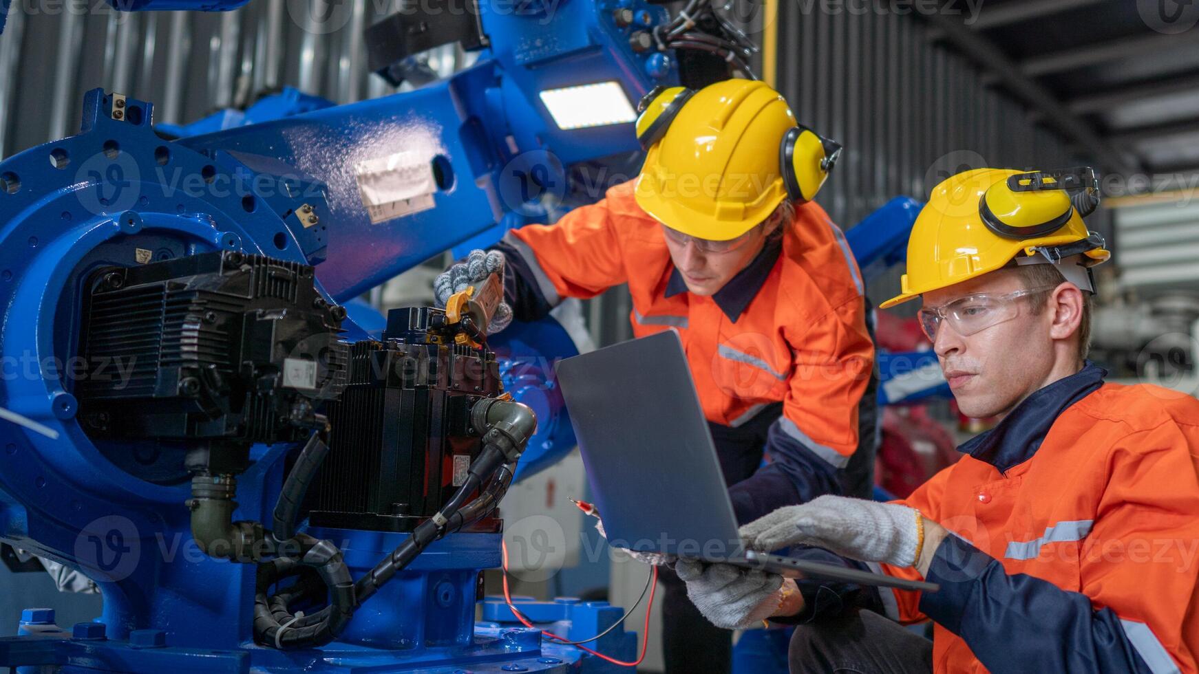group of male engineer workers maintenance automatic robotic arm machine in a dark room factory. worker checking and repairing automatic robot hand machine. Worker wearing safety glasses and helmet. photo