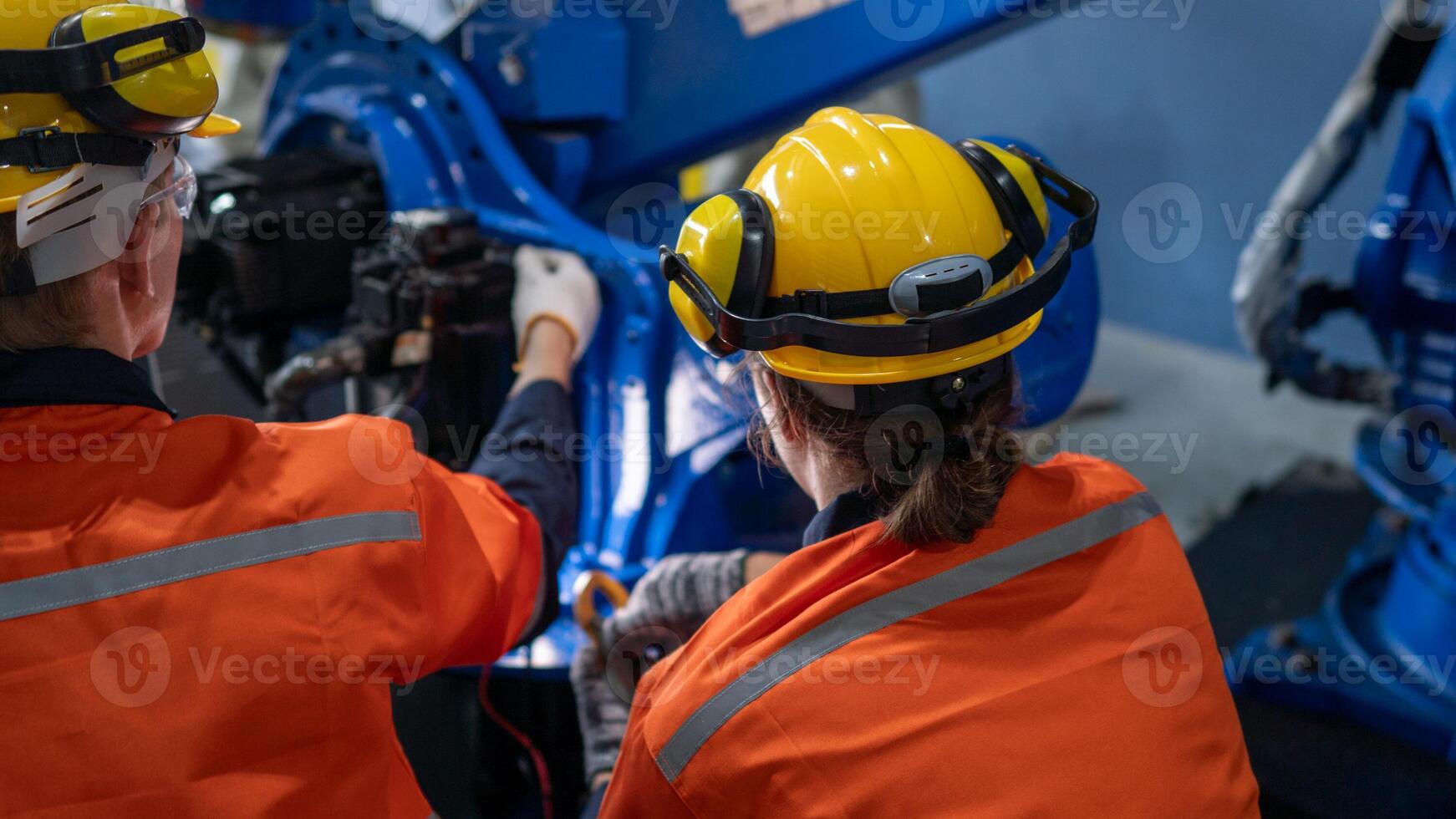 group of male engineer workers maintenance automatic robotic arm machine in a dark room factory. worker checking and repairing automatic robot hand machine. Worker wearing safety glasses and helmet. photo