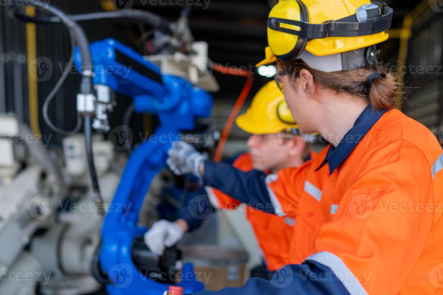 group of male engineer workers maintenance automatic robotic arm machine in a dark room factory. worker checking and repairing automatic robot hand machine. Worker wearing safety glasses and helmet. photo