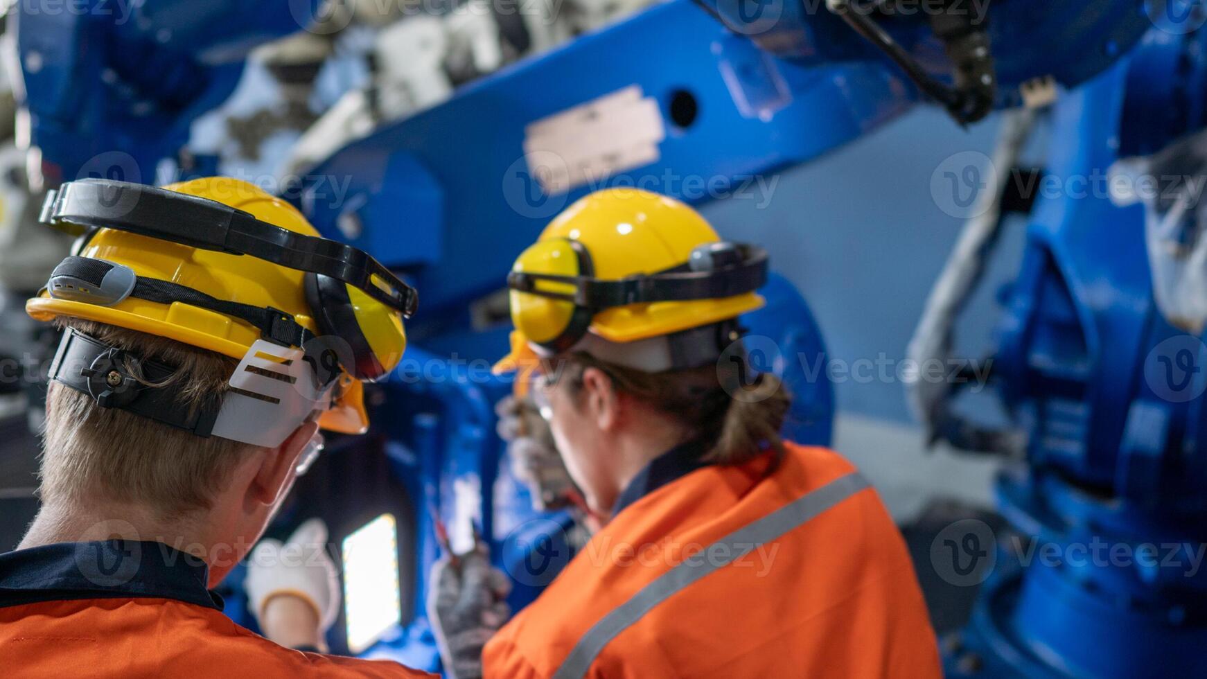 group of male engineer workers maintenance automatic robotic arm machine in a dark room factory. worker checking and repairing automatic robot hand machine. Worker wearing safety glasses and helmet. photo