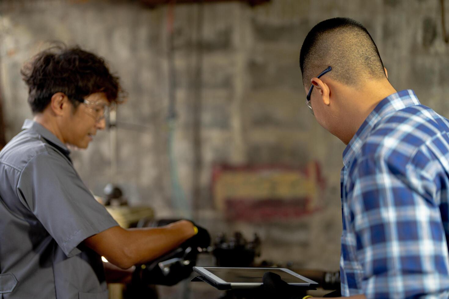 Men are inspecting steel parts for machine installation. team of teacher and student are learning to use heavy machines in steel factory. workers cooperate while doing quality control of manufactured. photo