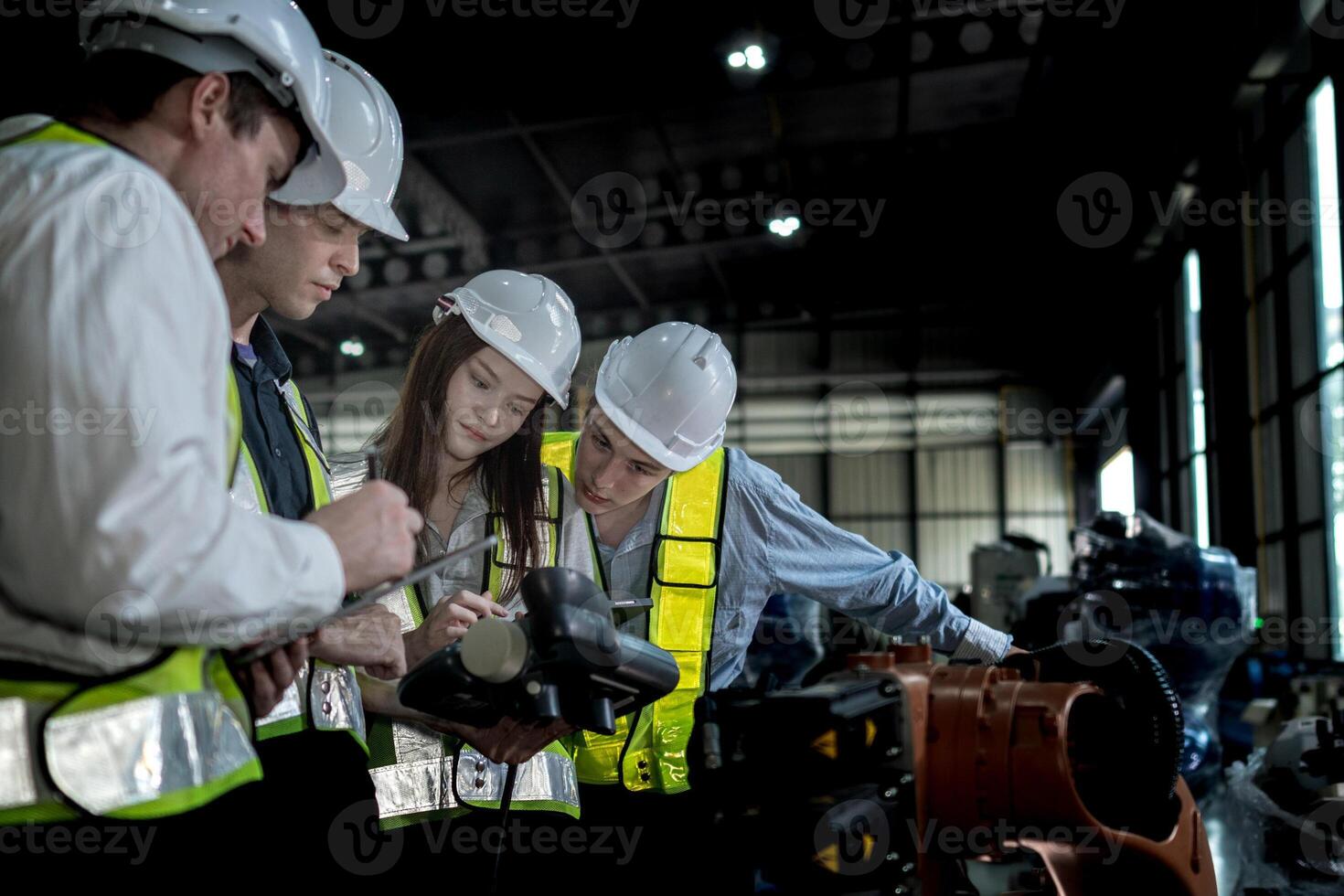 team engineers inspecting on machine with smart tablet. Worker works at heavy machine robot arm. The welding machine with a remote system in an industrial factory. Artificial intelligence concept. photo