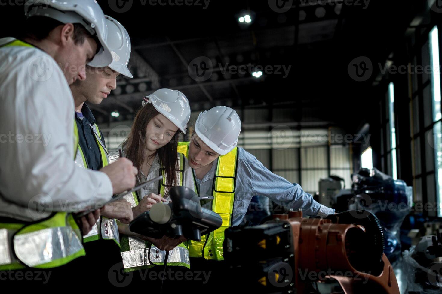 team engineers inspecting on machine with smart tablet. Worker works at heavy machine robot arm. The welding machine with a remote system in an industrial factory. Artificial intelligence concept. photo